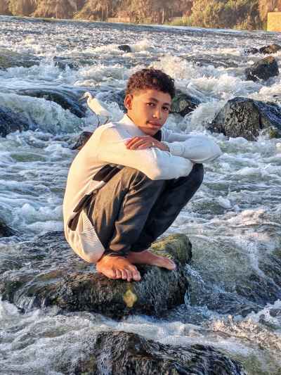 Young Man Sitting on Rock at Al-Qanater Al-Khayreya Rapids