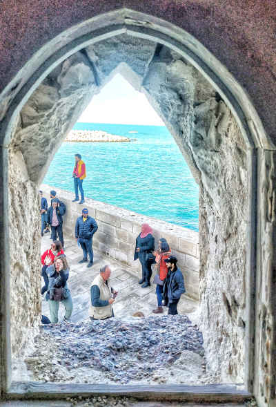 Tourists at Qaitbay Citadel Sea Wall Through Stone Arch