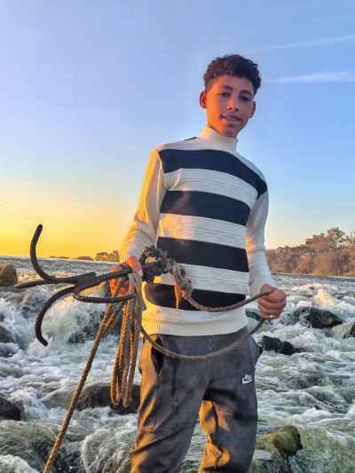 Young Man Holding Fishing Hook at Al-Qanater Waterfalls