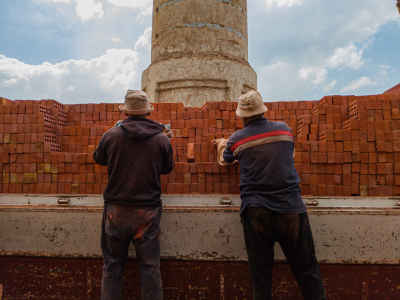 Two Egyptian Workers Unloading Red Bricks Outdoors