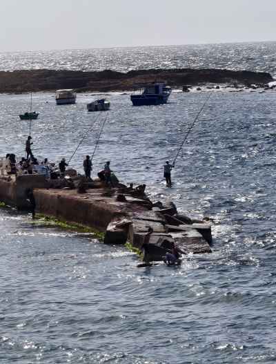 Fishermen Casting Lines from Stone Pier at Sea