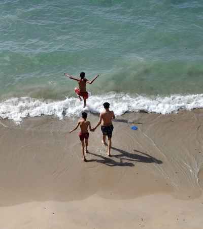 Kids Jumping Into Mediterranean Waves at Beach