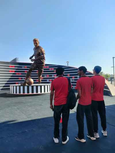 Young Fans View Football Player Statue at Fan Zone