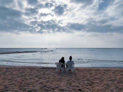 Two People Sitting Beachside Overlooking Calm Suez Canal