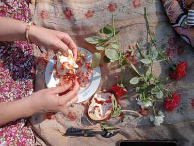 Girl Eating Pomegranate with Roses on Floral Tablecloth