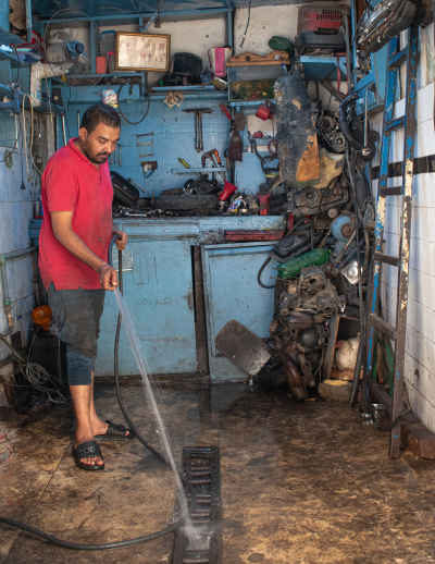 Motorcycle Mechanic Cleaning Workshop Floor, Cairo