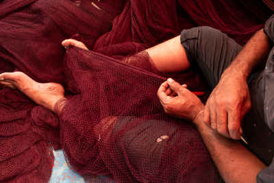 Fisherman Mending Red Fishing Net by Hand