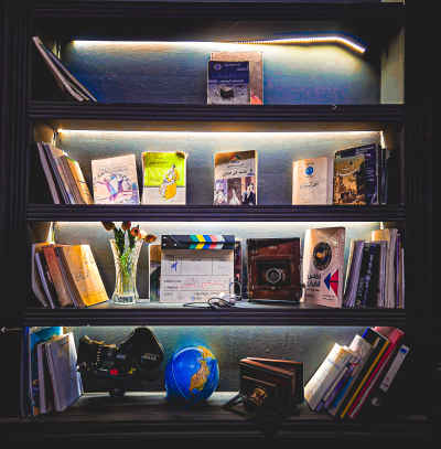Lit Bookshelf with Books Globe and Film Clapper