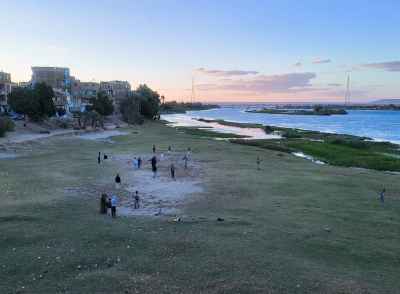 People Gathering Along the Nile River at Sunset in Qena, Egypt