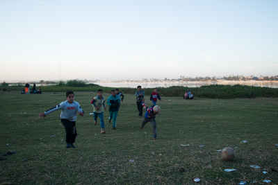 Children Chasing the Ball on an Open Football Field
