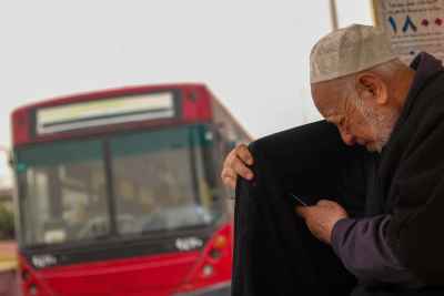 Elderly Man Checking His Phone Beside a City Bus 2