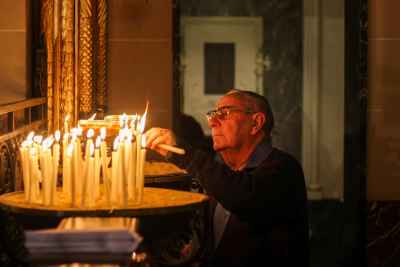 Elderly Man Lighting Candles in Church Prayer Ritual