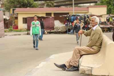 Elderly Man with Cane Sitting in Cairo Street Scene