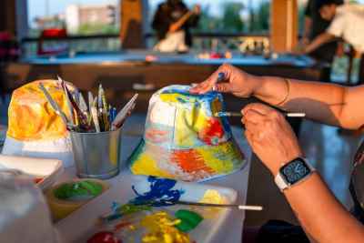 Image of a woman delicately painting a white hat