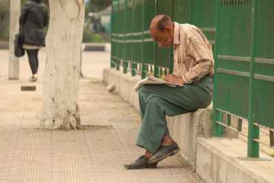 Man Reading a Newspaper in a Street in Cairo, Egypt