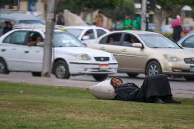 Man Resting on Grass Beside Traffic in Cairo
