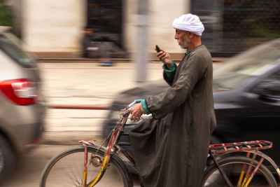 Man Riding a Bicycle While Checking His Phone in Cairo