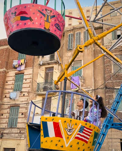 Two Kids Riding a “Moulid” Swing During Eid in Egypt