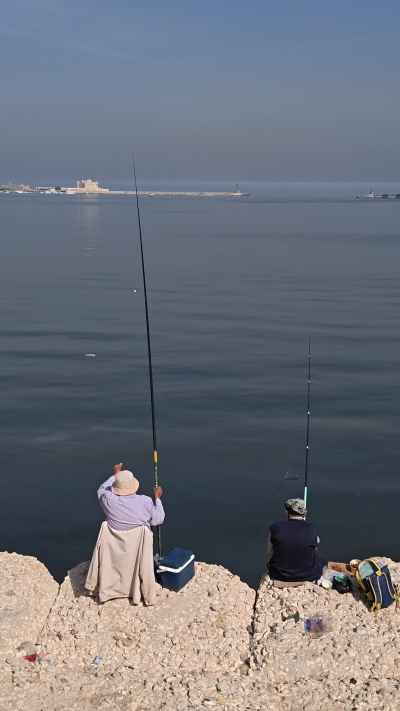 Fishermen on Alexandria Corniche with Qaitbay Citadel on the Horizon