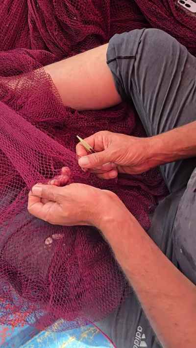 Egyptian Fisherman Mending Red Fishing Net by Hand