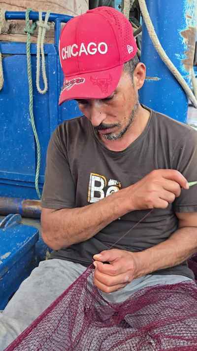 Egyptian Fisherman Mending Net on Fishing Boat