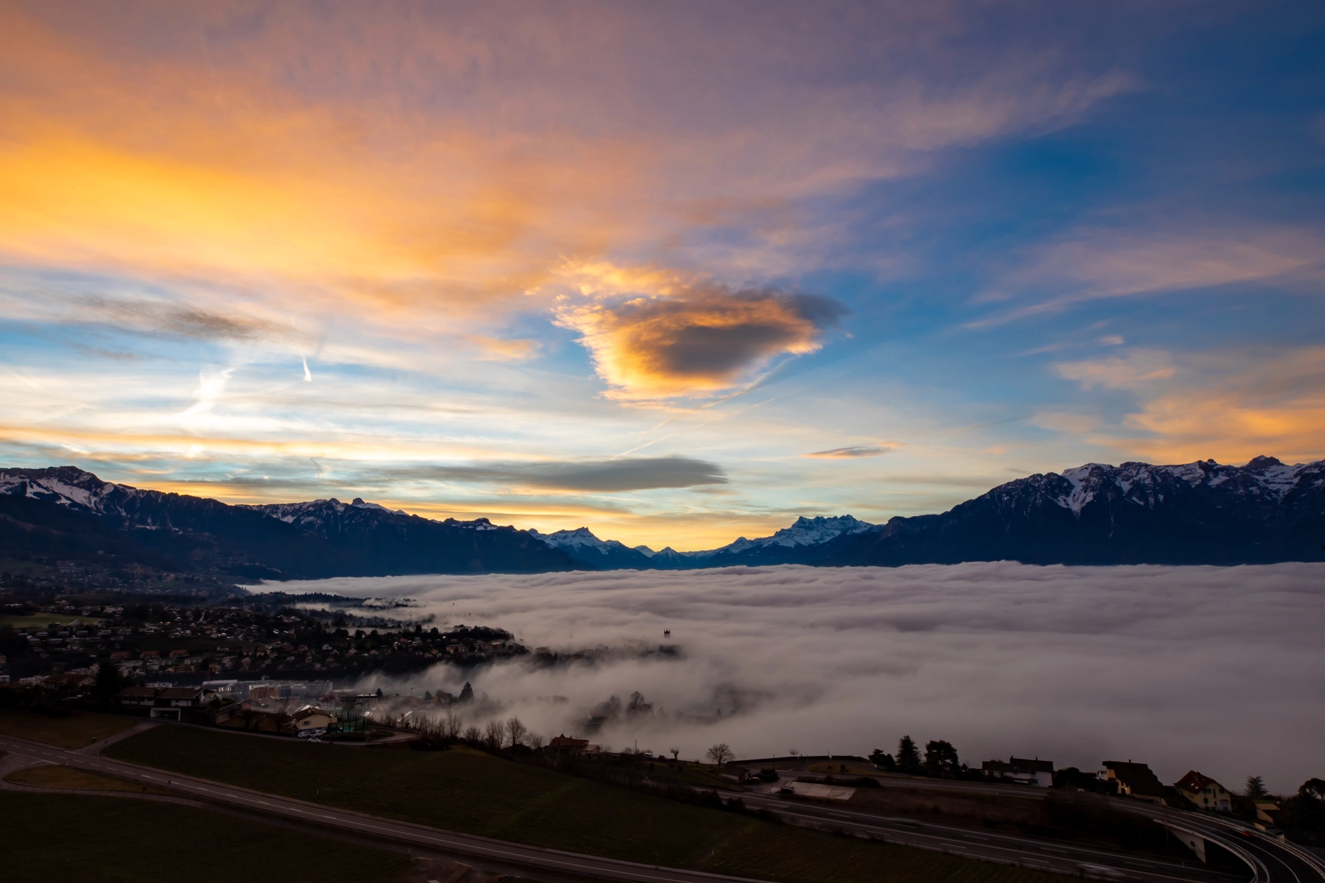 Morning Fog Blankets the Valley Beneath a Vibrant Alpine Sunrise