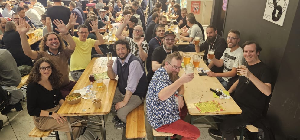 People enjoying drinks sitting on long wooden benches