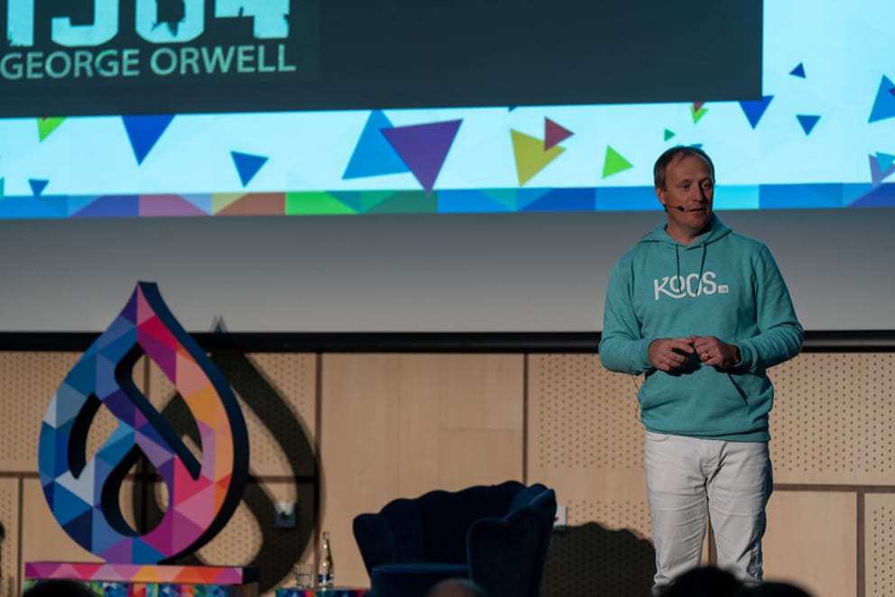 Man in turquoise hoodie giving a presentation