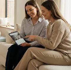 Two parents exploring childcare options together on a digital platform while their children play nearby, illustrating the guidance and support provided through the MyKids programme.