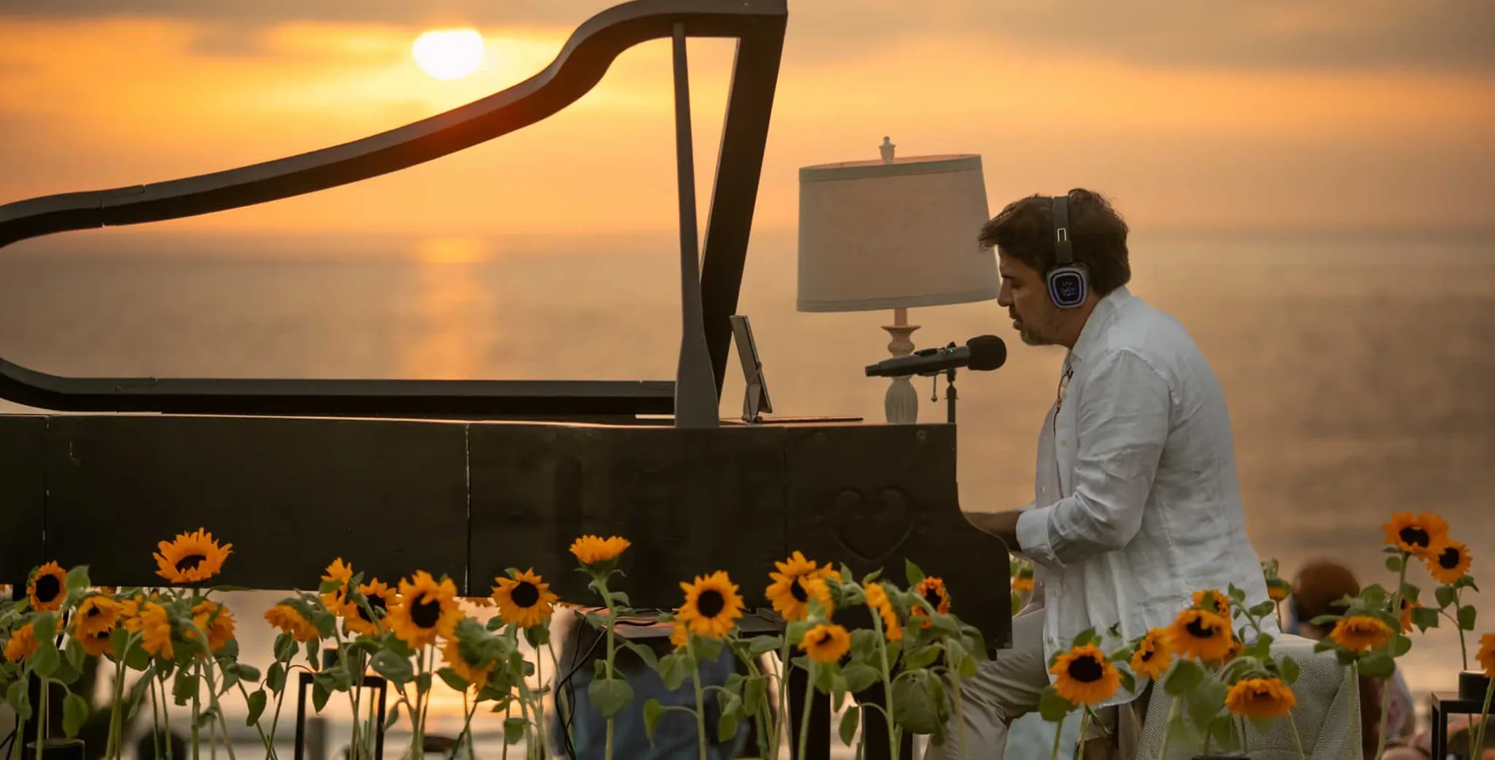 Murray Hidary playing piano at sunset among sunflowers