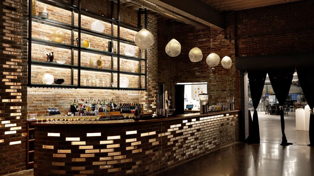 A lit back bar with bottles and brick walls