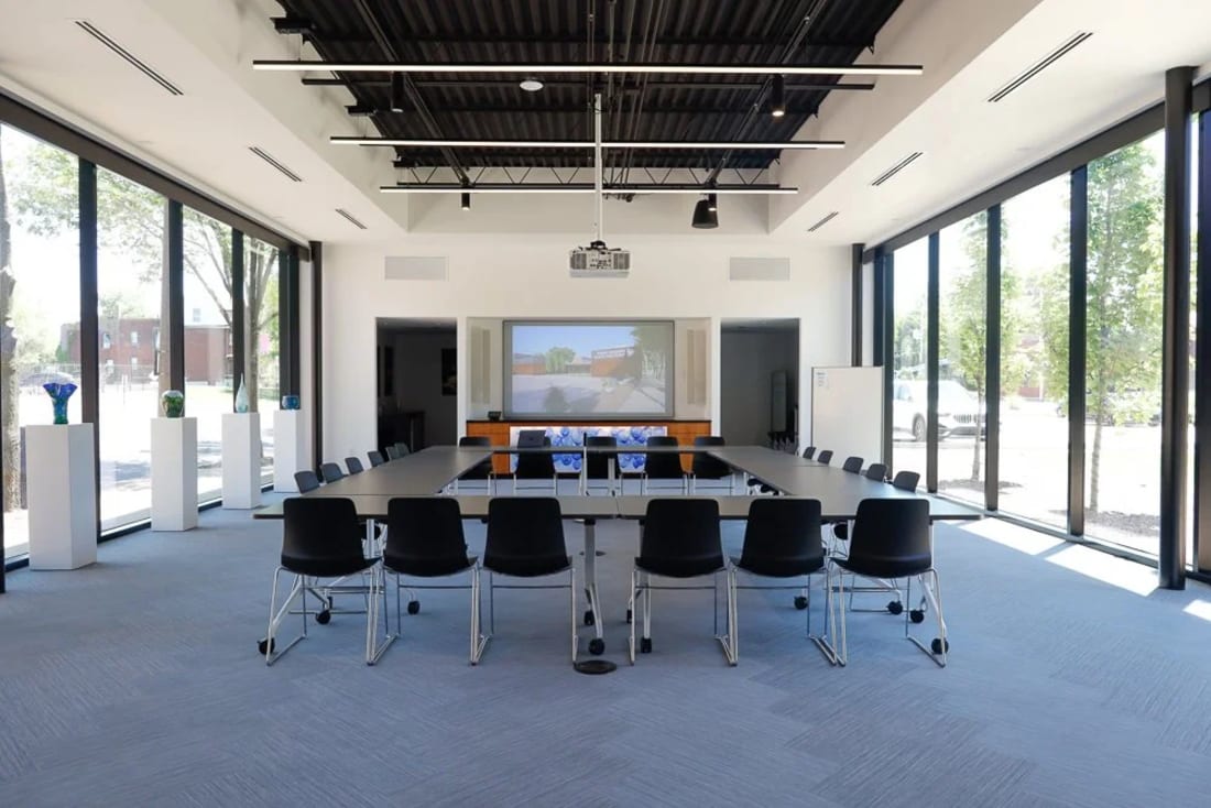 A meeting room set with a long table and screen