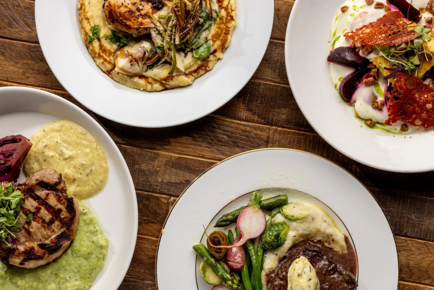 Plated dishes on a wood table from a Culinary Canvas event