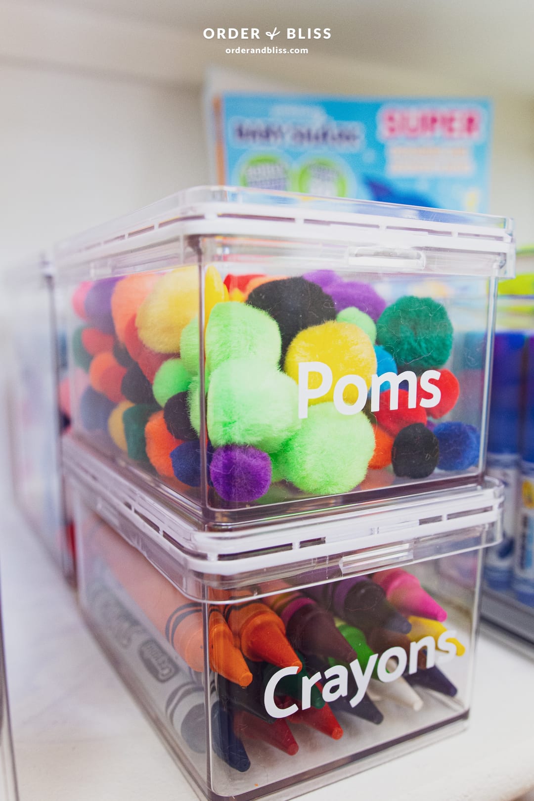 Clear organizing bins with poms and crayons