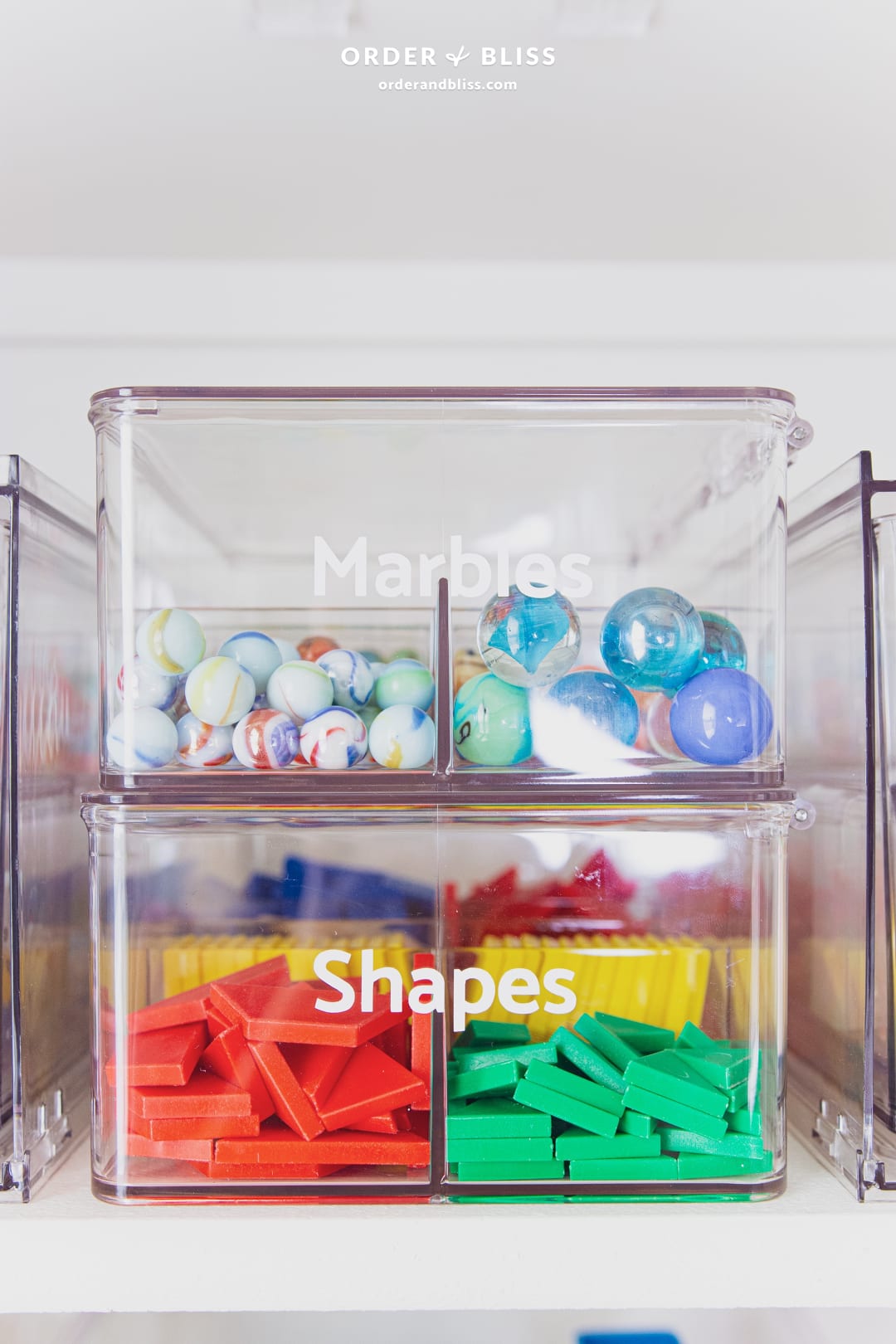 Clear stackable containers storing marbles and shapes