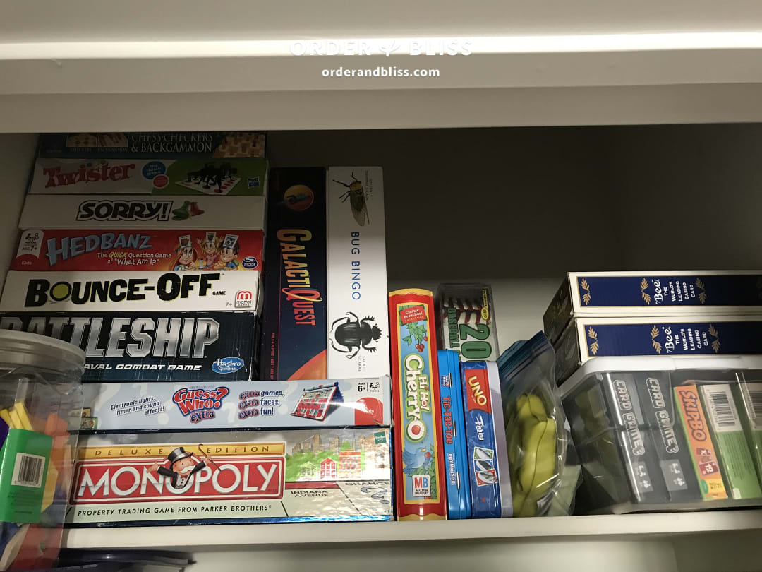 Before shelf of stacked board game boxes