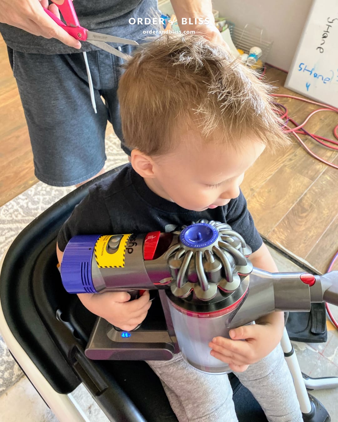 Toddler boy holding a vacuum during haricut