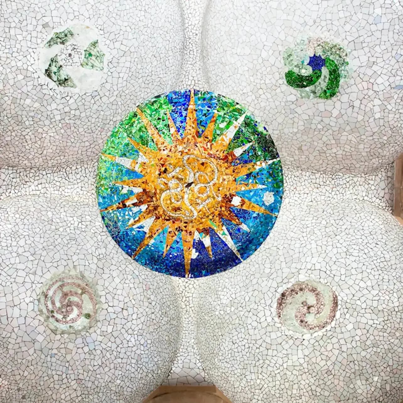 Sostre de mosaic amb un disseny central en forma de sol envoltat per quatre patrons circulars en tons verds i porpres.