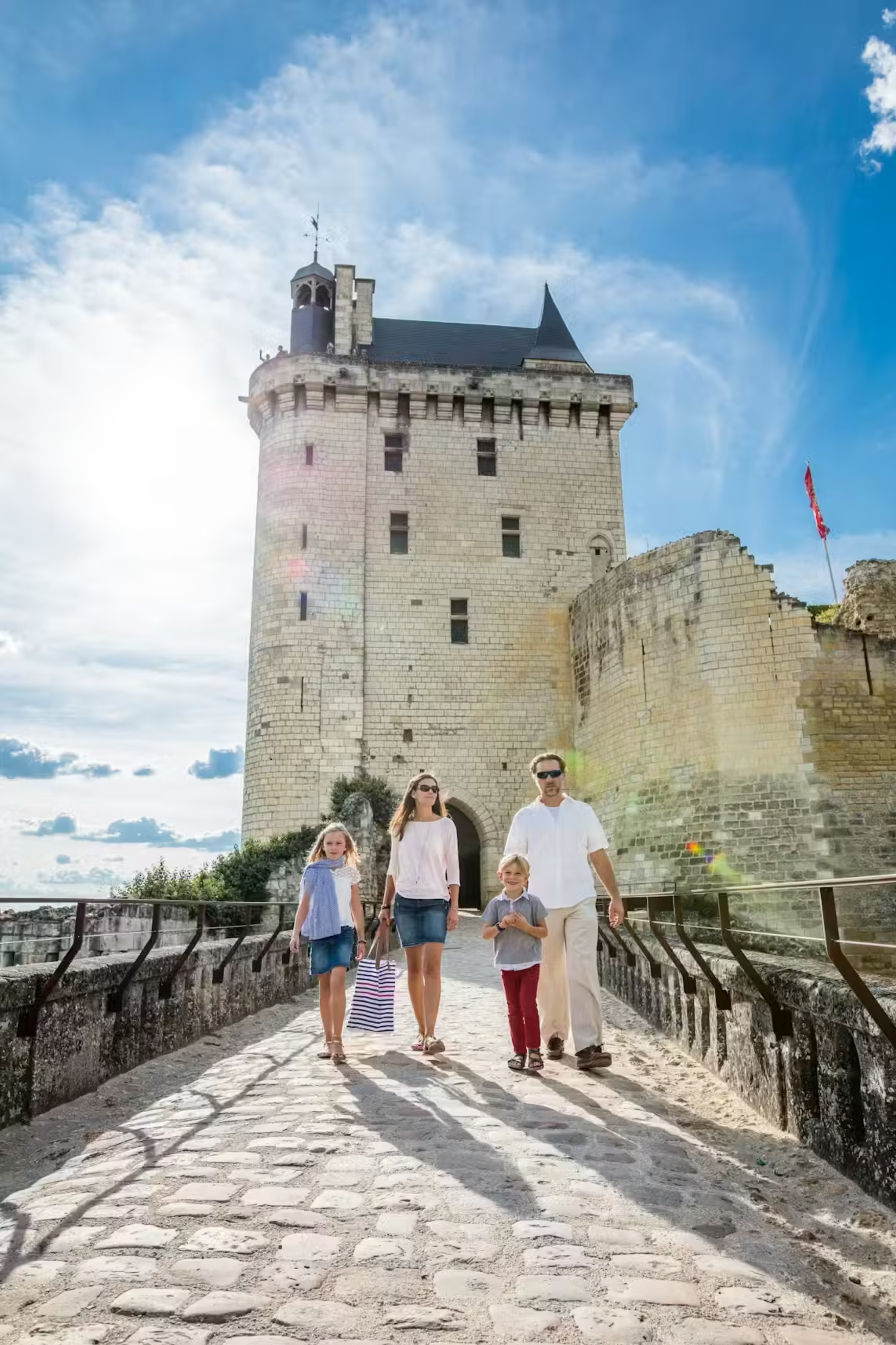 Famille visitant un château de la Loire avec des enfants jouant dans les jardins