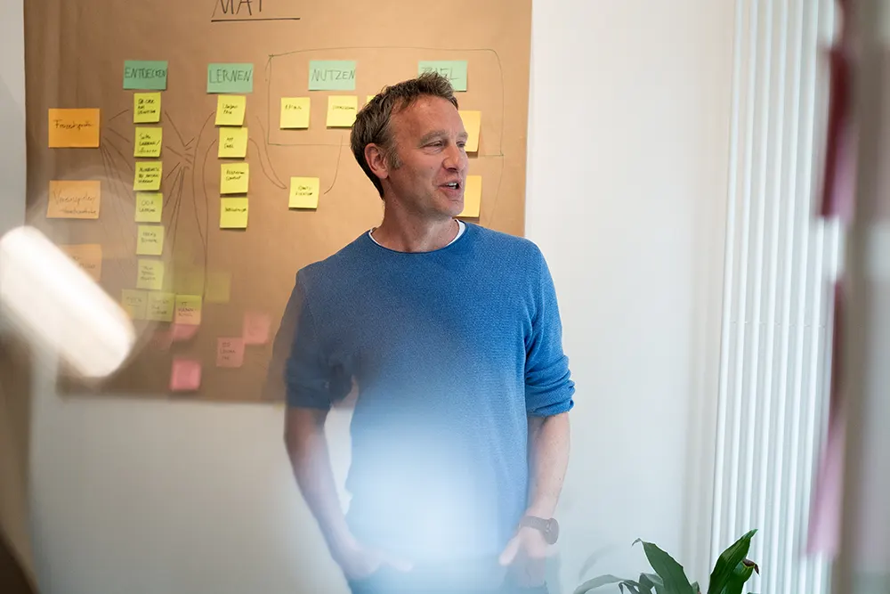 Das Foto zeigt einen Workshop-Teilnehmer vor einer Post-it Wand.