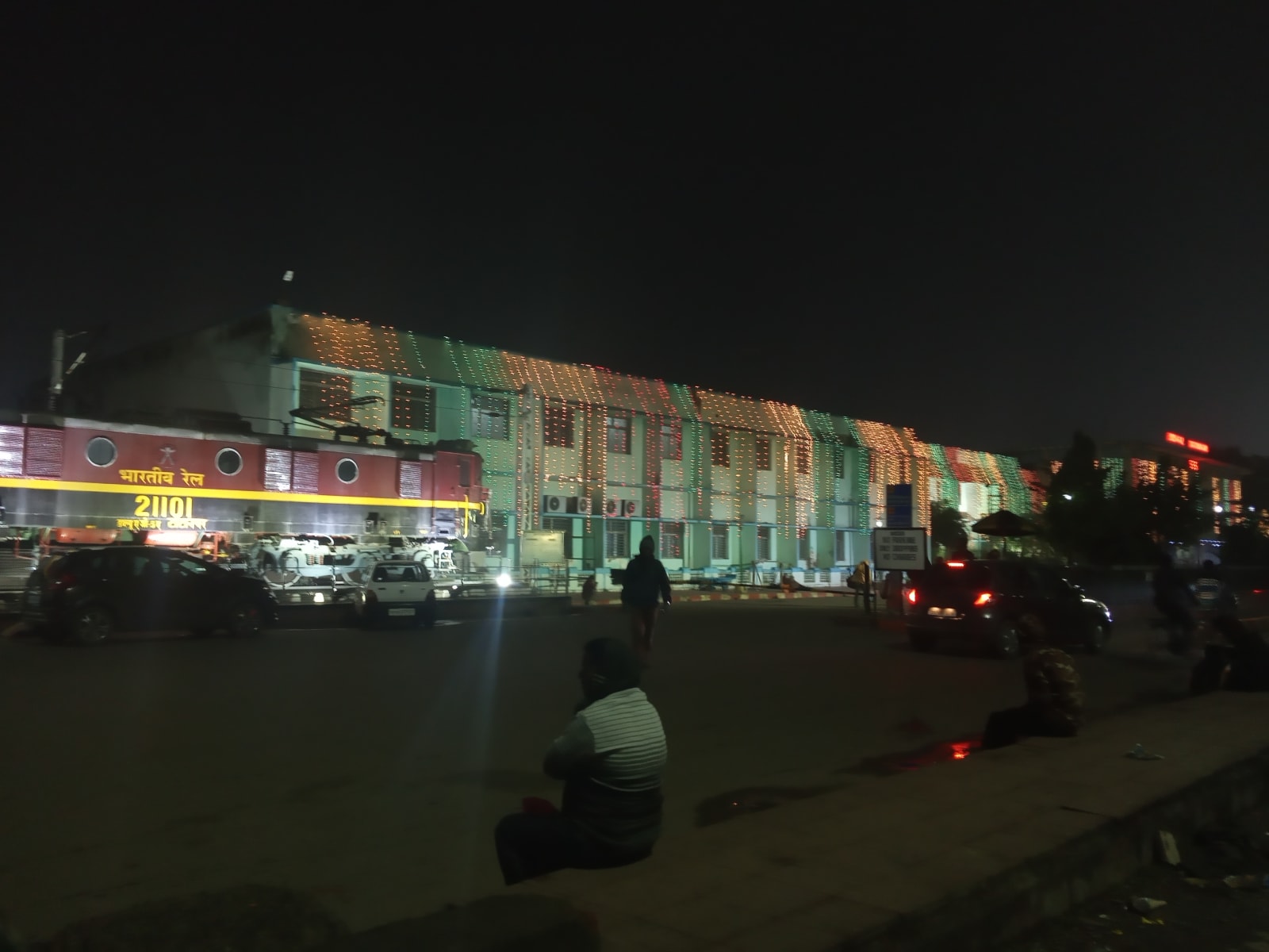 Historical Tatanagar station forecourt at night with vehicles and a locomotive display