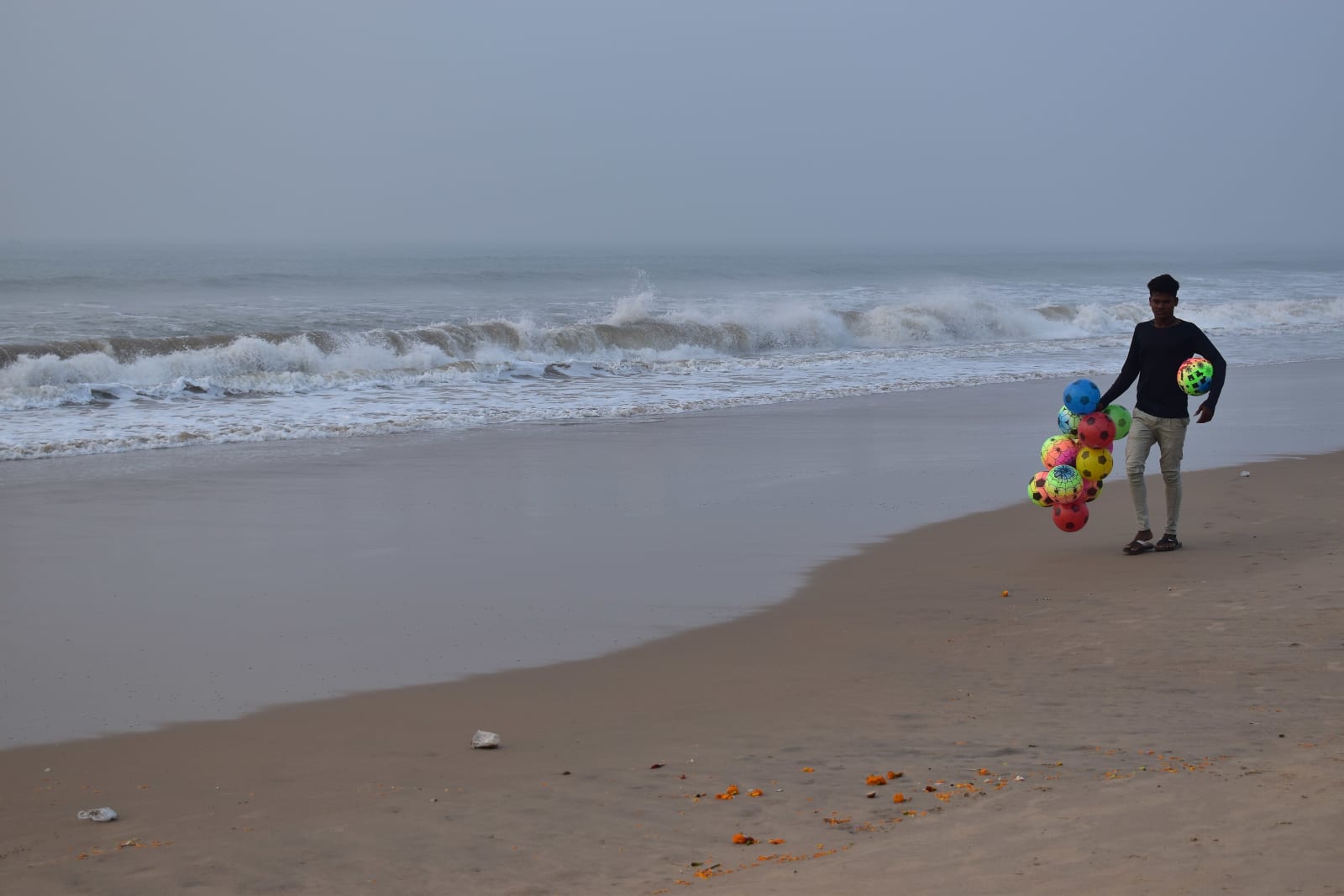 Waves and a beach vendor on Puri Golden Beach in January 2021