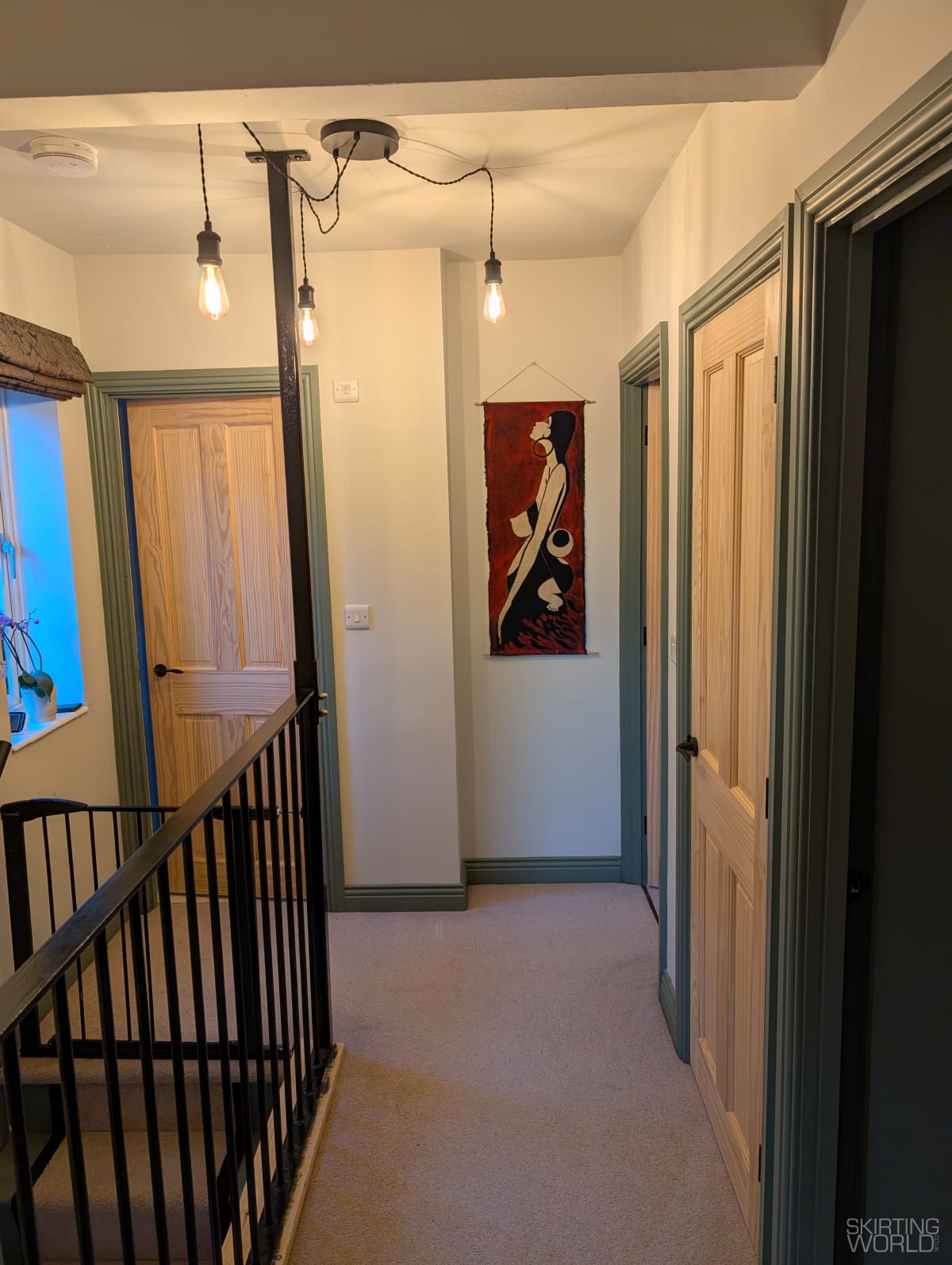 Muted green Regency MDF architrave in a hallway with cream walls and pine doors