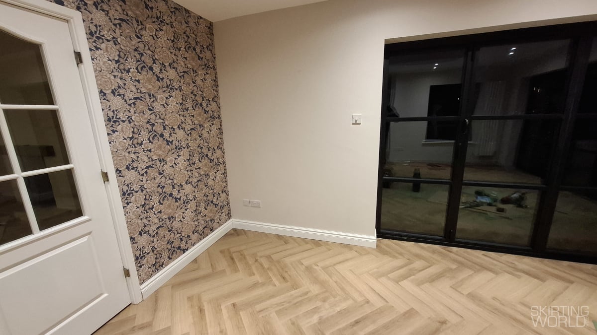 White 330 MDF skirting board in a living room with floral wallpaper, cream tones, and a feature wall