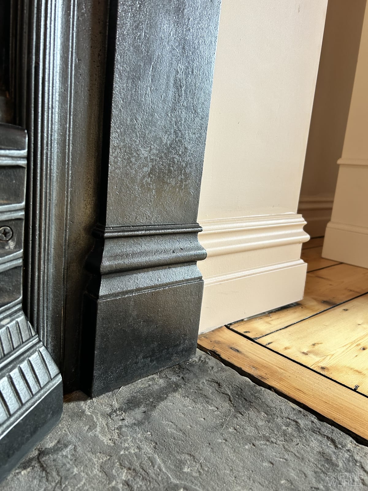 Tall Period MDF skirting board meeting a cast iron fireplace and flagstone hearth in a renovated British period interior