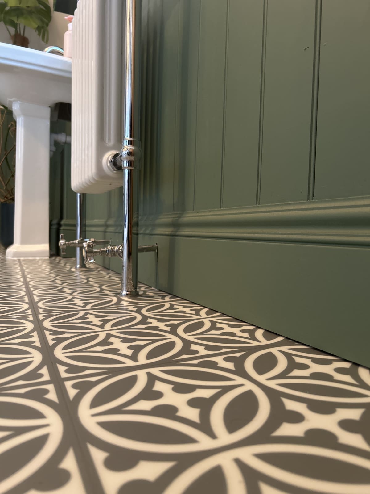 Green-painted MDF board and batten panelling above a tall skirting board in a real bathroom