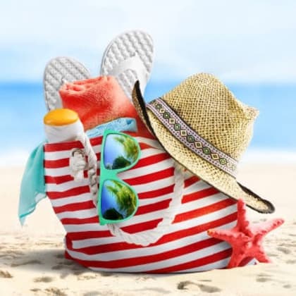 Red-and-white striped beach bag with a straw hat, flip-flops, sunglasses, and a starfish on the sand
