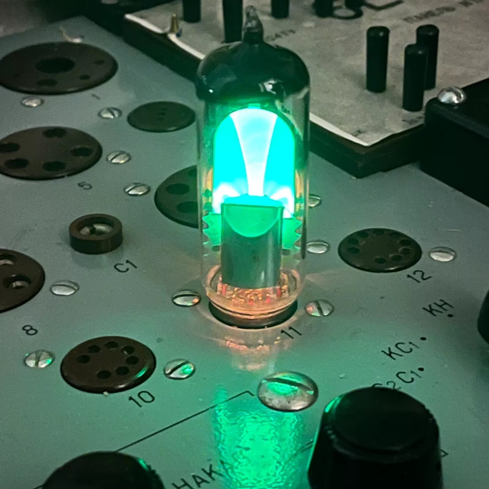 A Soviet 6E1P / EM80 magic eye lit green in the tester socket panel