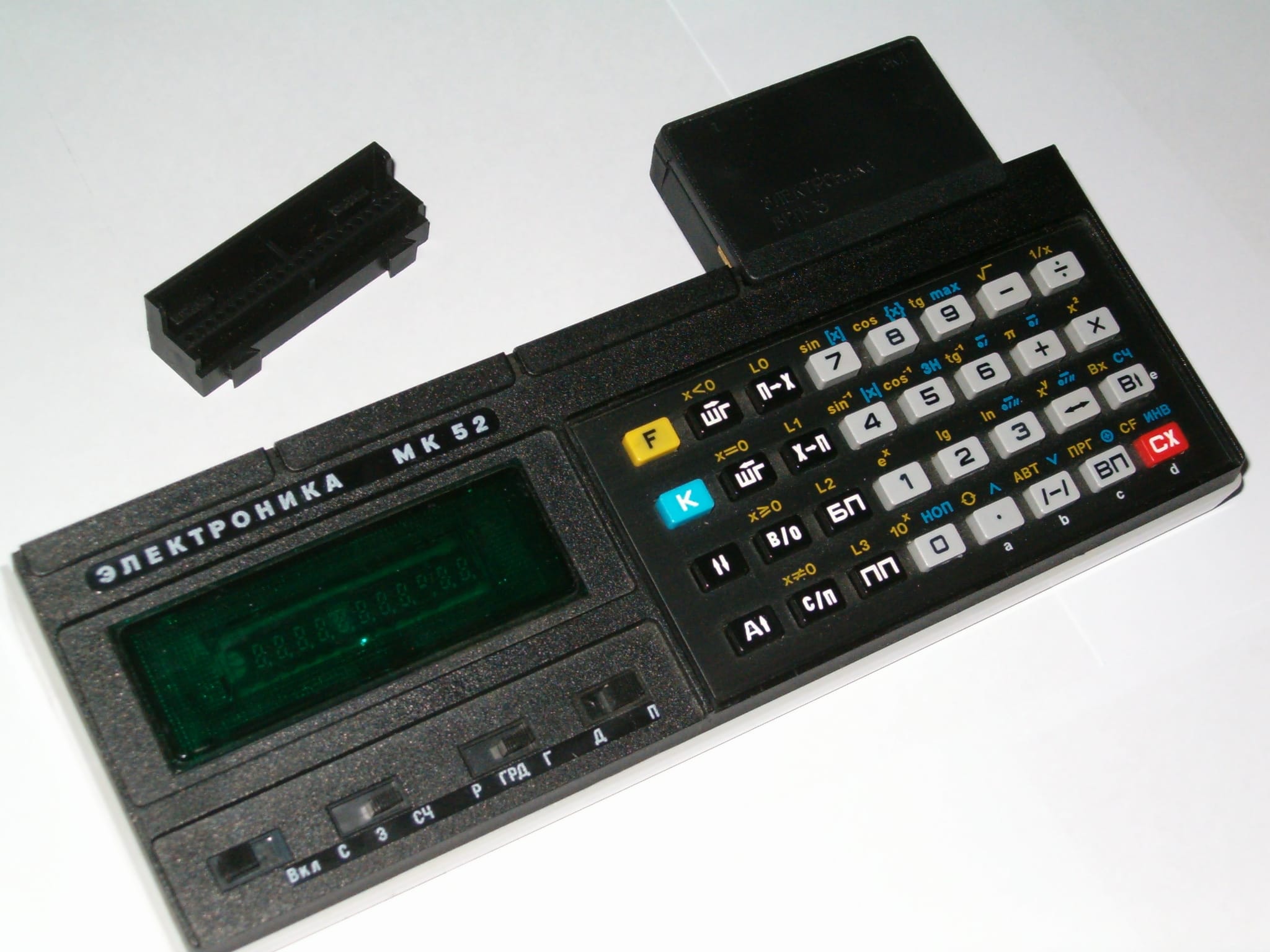Elektronika MK-52 programmable calculator with its expansion socket open and a BRP-3 ROM cartridge module beside it