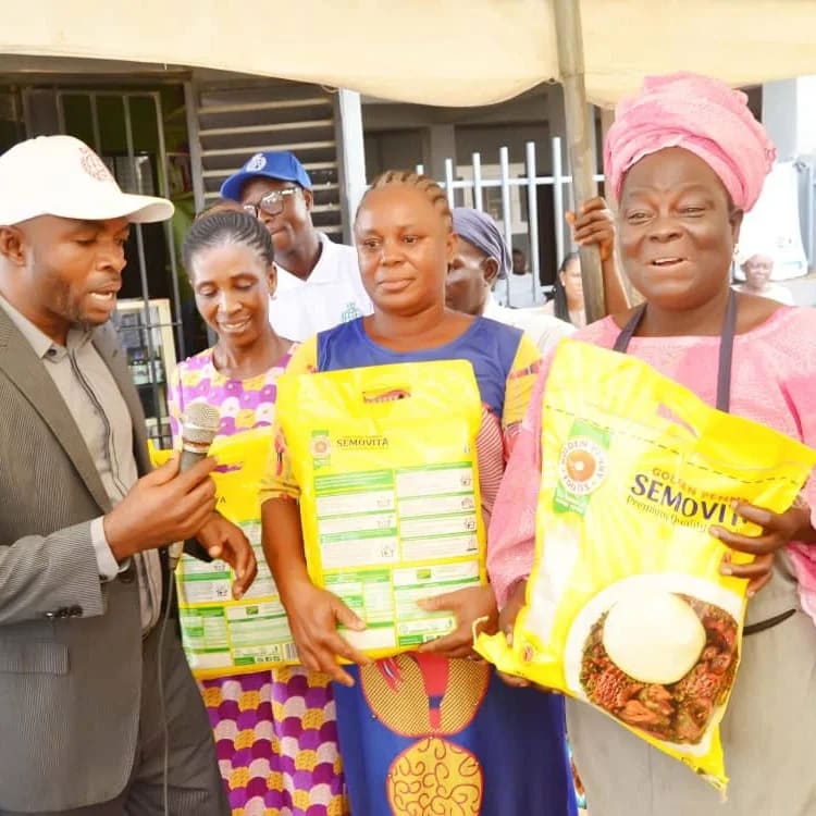 Smiling women holding bags of rice and Semovita they received from the foundation